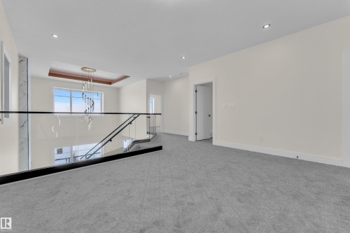 Carpeted empty room featuring a raised ceiling and hanging lights - 231 Crystal Creek Drive, Leduc, AB - Indoor Photo Showing Other Room