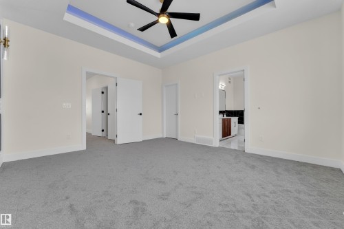 Unfurnished living room with a raised ceiling, light colored carpet, and ceiling fan - 231 Crystal Creek Drive, Leduc, AB - Indoor Photo Showing Other Room
