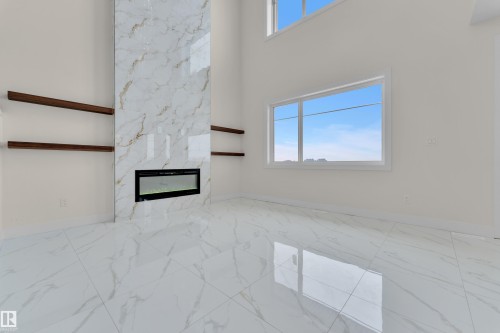 Unfurnished living room featuring a high ceiling, a premium fireplace, and light marble finish flooring - 231 Crystal Creek Drive, Leduc, AB - Indoor Photo Showing Other Room