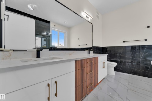 Full bathroom featuring tile walls, double vanity, a shower stall, a wainscoted wall, and light marble finish floors - 231 Crystal Creek Drive, Leduc, AB - Indoor Photo Showing Bathroom