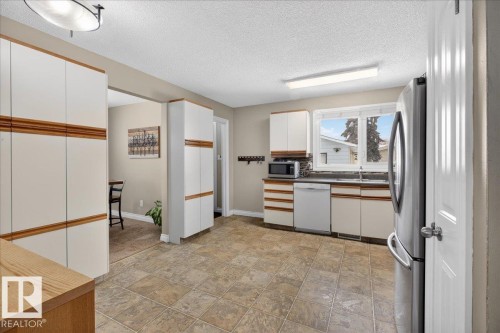 Dual tone kitchen with dual tone cabinets, a textured ceiling, stainless steel appliances, stone finish floors, and tasteful backsplash - 8804 38 Avenue, Edmonton, AB - Indoor Photo Showing Kitchen
