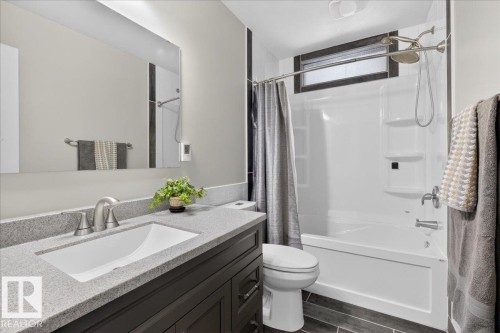 Full bath with vanity, shower / tub combo, and wood finish floors - 8804 38 Avenue, Edmonton, AB - Indoor Photo Showing Bathroom