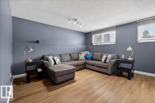 Living room with wood finished floors, a textured ceiling, and rail lighting - 8804 38 Avenue, Edmonton, AB - Indoor Photo Showing Living Room