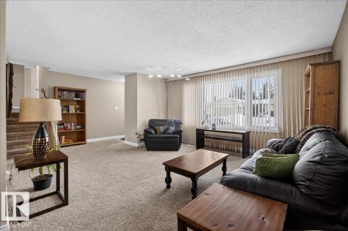 Carpeted living area with a textured ceiling and stairway - 8804 38 Avenue, Edmonton, AB - Indoor Photo Showing Living Room
