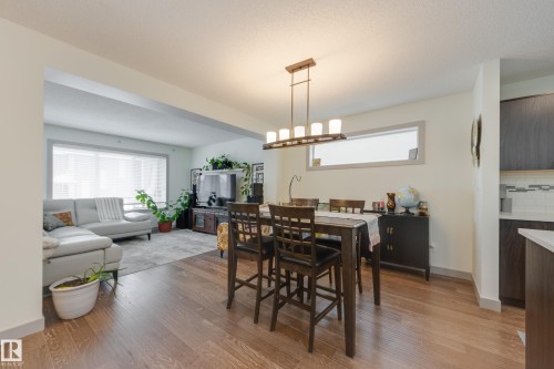Dining space featuring light wood finished floors, hanging lights, and a textured ceiling - 17528 58 Street, Edmonton, AB - Indoor