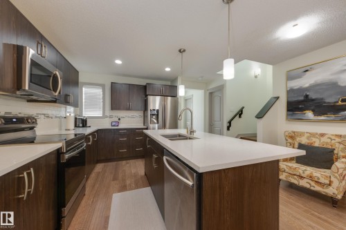 Kitchen with stainless steel appliances, dark wood-style flooring, dark wood finish cabinets, hanging light fixtures, and a textured ceiling - 17528 58 Street, Edmonton, AB - Indoor Photo Showing Kitchen With Stainless Steel Kitchen With Double Sink With Upgraded Kitchen