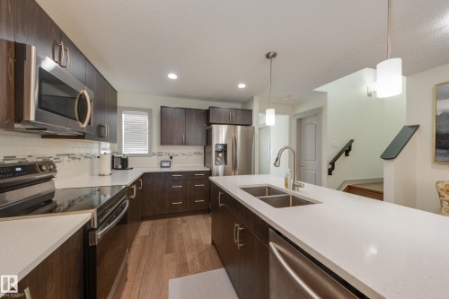 Kitchen featuring stainless steel appliances, dark wood finish cabinetry, pendant lighting, dark wood finished floors, and tasteful backsplash - 17528 58 Street, Edmonton, AB - Indoor Photo Showing Kitchen With Stainless Steel Kitchen With Double Sink With Upgraded Kitchen