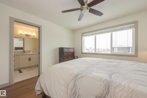 Bedroom featuring ceiling fan, wood finished floors, a textured ceiling, and connected bathroom - 17528 58 Street, Edmonton, AB - Indoor Photo Showing Bedroom