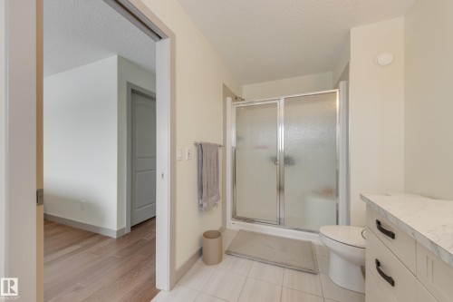 Full bath with a textured ceiling, a stall shower, vanity, and light tile patterned flooring - 17528 58 Street, Edmonton, AB - Indoor Photo Showing Bathroom