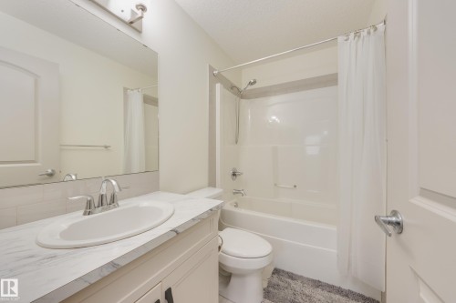 Bathroom featuring vanity, shower / tub combo, and a textured ceiling - 17528 58 Street, Edmonton, AB - Indoor Photo Showing Bathroom