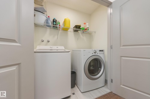 Laundry area with independent washer and dryer and light tile patterned floors - 17528 58 Street, Edmonton, AB - Indoor Photo Showing Laundry Room
