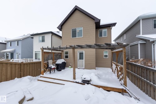 Snow covered house featuring a fenced backyard, a deck, and a pergola - 17528 58 Street, Edmonton, AB - Outdoor With Exterior