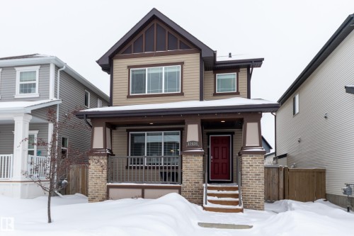 View of front of home featuring covered porch, brick siding, and board and batten siding - 17528 58 Street, Edmonton, AB - Outdoor With Facade