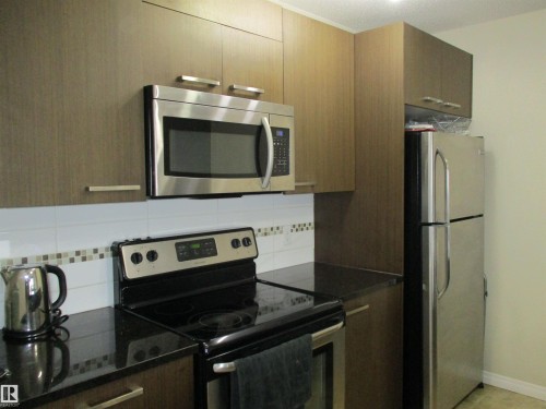 Kitchen with stainless steel appliances, tasteful backsplash, dark stone counters, and modern cabinets - 3309 9351 Simpson Drive, Edmonton, AB - Indoor Photo Showing Kitchen