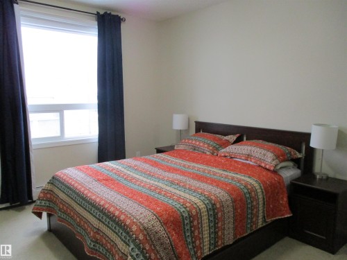 Bedroom with light carpet and multiple windows - 3309 9351 Simpson Drive, Edmonton, AB - Indoor Photo Showing Bedroom