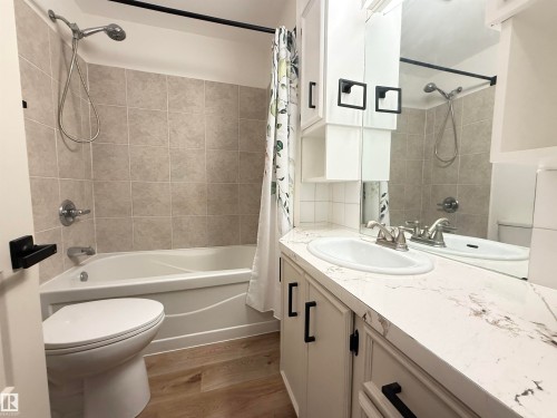 Full bathroom featuring vanity, shower / tub combo with curtain, and dark wood-style floors - 9034 60 Street, Edmonton, AB - Indoor Photo Showing Bathroom