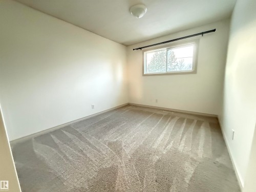 Unfurnished room featuring light carpet and baseboards - 9034 60 Street, Edmonton, AB - Indoor Photo Showing Other Room