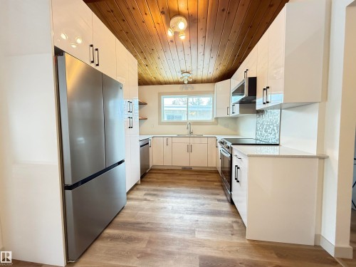 Kitchen featuring stainless steel appliances, light wood-style floors, white cabinetry, wooden ceiling, and open shelves - 9034 60 Street, Edmonton, AB - Indoor Photo Showing Kitchen