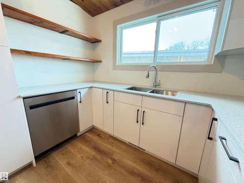 Kitchen featuring open shelves, white cabinetry, stainless steel dishwasher, light stone countertops, and light wood-style flooring - 9034 60 Street, Edmonton, AB - Indoor Photo Showing Kitchen With Double Sink