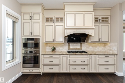 Kitchen featuring glass fronted cabinets, double oven, light stone counters, and cream cabinetry - 3520 Watson Point(E), Edmonton, AB - Indoor Photo Showing Kitchen