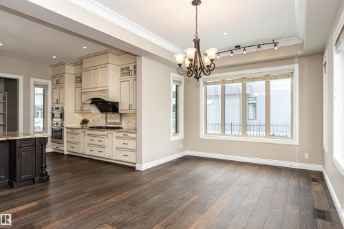 Unfurnished dining area with dark wood-style floors, hanging lights, and crown molding - 3520 Watson Point(E), Edmonton, AB - Indoor