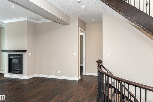 Unfurnished living room featuring a glass covered fireplace, dark wood finished floors, recessed lighting, and a textured ceiling - 3520 Watson Point(E), Edmonton, AB - Indoor Photo Showing Other Room With Fireplace