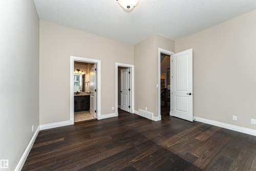 Unfurnished bedroom with dark wood-style flooring, a textured ceiling, and ensuite bath - 3520 Watson Point(E), Edmonton, AB - Indoor Photo Showing Other Room