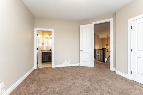 Unfurnished bedroom with a chandelier, light colored carpet, ensuite bath, and a textured ceiling - 3520 Watson Point(E), Edmonton, AB - Indoor Photo Showing Other Room