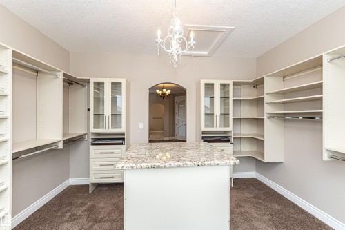Walk in closet featuring hanging lights, dark colored carpet, and arched walkways - 3520 Watson Point(E), Edmonton, AB - Indoor