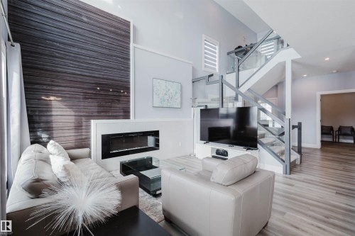 Living room featuring a glass covered fireplace, wood finished floors, and a high ceiling - 16217 32 Avenue, Edmonton, AB - Indoor Photo Showing Living Room With Fireplace