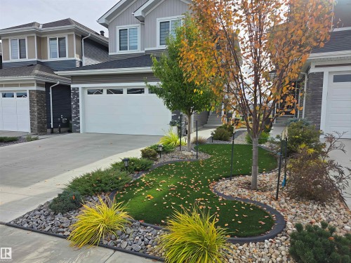View of front of home with concrete driveway, board and batten siding, an attached garage, and a front yard - 16217 32 Avenue, Edmonton, AB - Outdoor With Facade