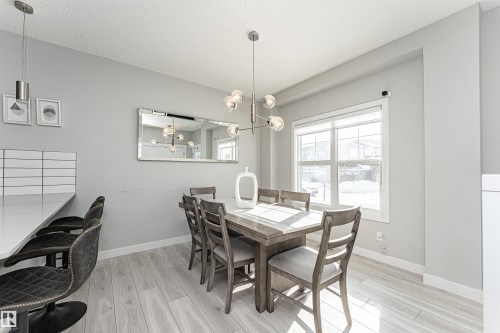 Dining space featuring light wood-type flooring, a chandelier, and a textured ceiling - 16616 31 Avenue, Edmonton, AB - Indoor Photo Showing Dining Room