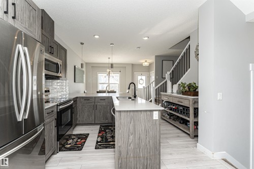 Kitchen featuring stainless steel appliances, light wood-style floors, a peninsula, pendant lighting, and backsplash - 16616 31 Avenue, Edmonton, AB - Indoor Photo Showing Kitchen With Upgraded Kitchen