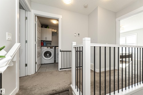Laundry area with light colored carpet, a textured ceiling, and cabinet space - 16616 31 Avenue, Edmonton, AB - Indoor Photo Showing Laundry Room