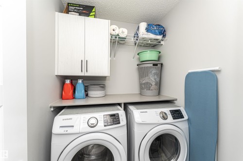Laundry area featuring cabinet space, washing machine and clothes dryer, and a textured ceiling - 16616 31 Avenue, Edmonton, AB - Indoor Photo Showing Laundry Room
