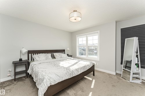 Carpeted bedroom featuring a textured ceiling and baseboards - 16616 31 Avenue, Edmonton, AB - Indoor Photo Showing Bedroom