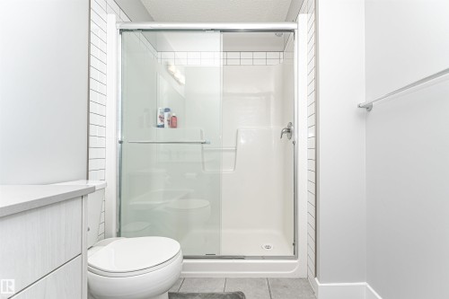 Bathroom with a shower stall, light tile patterned floors, and a textured ceiling - 16616 31 Avenue, Edmonton, AB - Indoor Photo Showing Bathroom