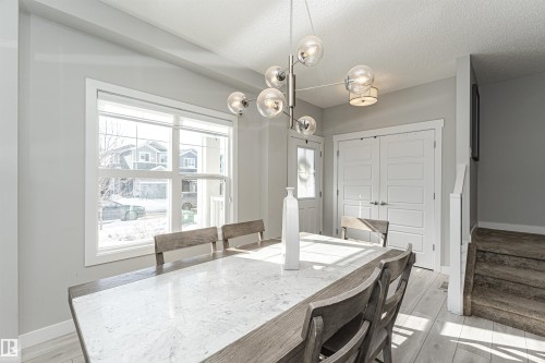 Dining room with light wood finished floors, hanging lights, and a textured ceiling - 16616 31 Avenue, Edmonton, AB - Indoor