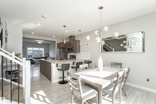 Dining area with light wood-style floors, hanging lights, and a textured ceiling - 16616 31 Avenue, Edmonton, AB - Indoor Photo Showing Dining Room