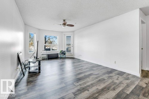 Exercise area with a textured ceiling, ceiling fan, and dark wood-type flooring - 101 400 Silver Berry Road, Edmonton, AB - Indoor Photo Showing Other Room