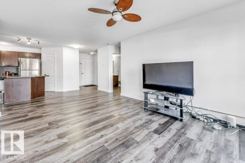 Unfurnished living room with ceiling fan, a textured ceiling, and light wood finished floors - 101 400 Silver Berry Road, Edmonton, AB - Indoor