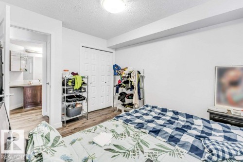 Bedroom with a textured ceiling, light wood-style floors, a closet, and connected bathroom - 101 400 Silver Berry Road, Edmonton, AB - Indoor Photo Showing Bedroom