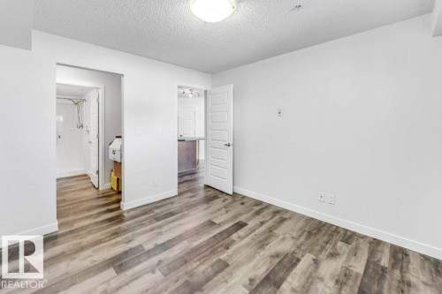 Unfurnished bedroom featuring a textured ceiling and wood finished floors - 101 400 Silver Berry Road, Edmonton, AB - Indoor Photo Showing Other Room