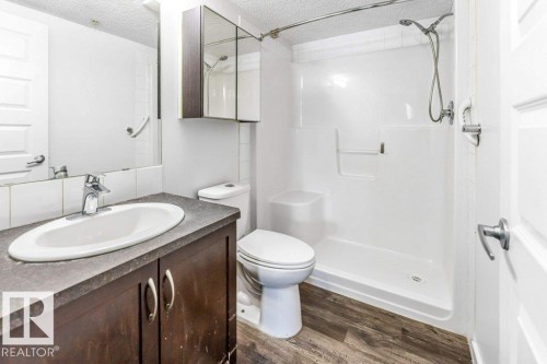 Bathroom with vanity, a stall shower, dark wood-style floors, and a textured ceiling - 101 400 Silver Berry Road, Edmonton, AB - Indoor Photo Showing Bathroom