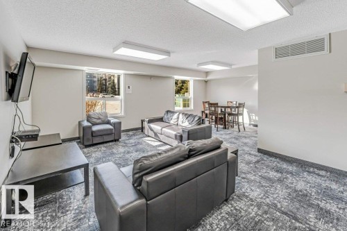 Carpeted living room with a textured ceiling - 101 400 Silver Berry Road, Edmonton, AB - Indoor Photo Showing Living Room