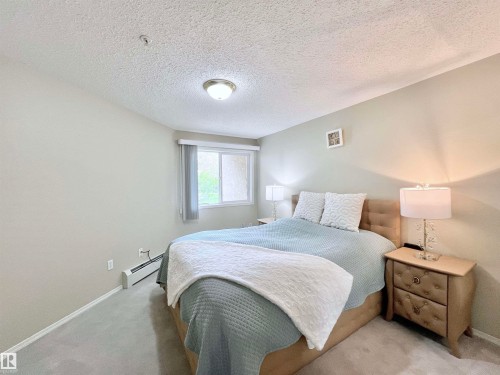 Bedroom featuring a textured ceiling, a baseboard heating unit, and carpet floors - 110 10511 42 Avenue, Edmonton, AB - Indoor Photo Showing Bedroom