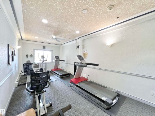 Workout room with a textured wall, a textured ceiling, and a ceiling fan - 110 10511 42 Avenue, Edmonton, AB - Indoor Photo Showing Gym Room