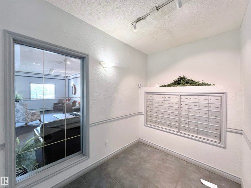 View of home's community with rail lighting, a textured wall, mail area, and a textured ceiling - 110 10511 42 Avenue, Edmonton, AB - Indoor Photo Showing Other Room