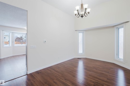Unfurnished dining area with dark wood finished floors, a chandelier, and lofted ceiling - 243 Rhatigan Road E, Edmonton, AB - Indoor Photo Showing Other Room