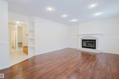 Unfurnished living room with a tile fireplace, wood finished floors, and recessed lighting - 243 Rhatigan Road E, Edmonton, AB - Indoor Photo Showing Living Room With Fireplace